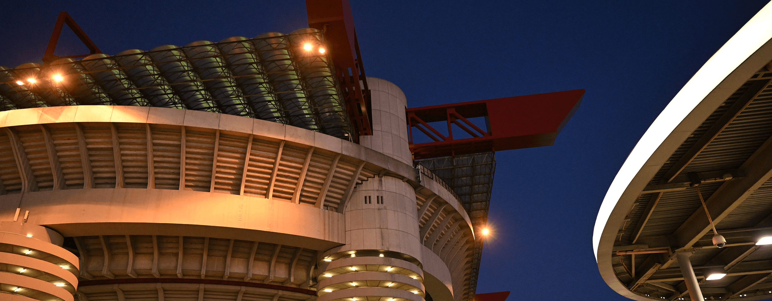 Vista esterna serale di San Siro illuminato, dettaglio delle torri e delle strutture rosse